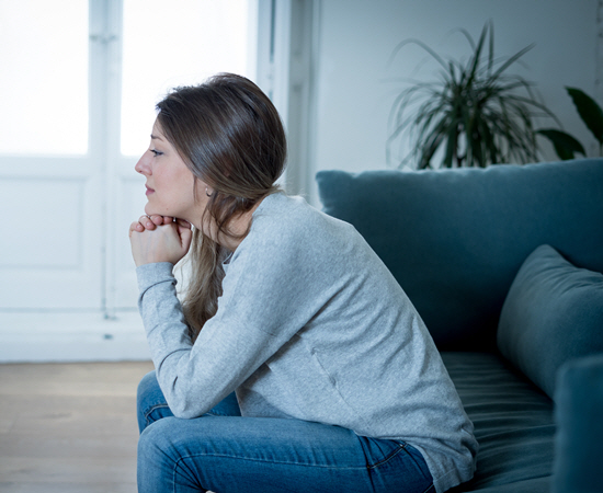 A woman sits with her head on her hands, thinking.