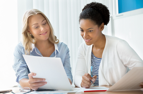 Two woman review paperwork together