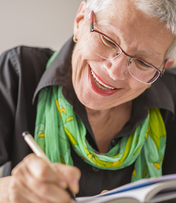 An elderly woman with a bright green scarf fills out paperwork