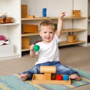 child toddler plays with balls and cylinders, developing sensory activities in montessori and earlier development of children, independence of babies