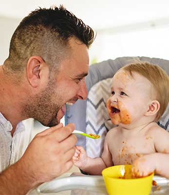 A man feeding a baby