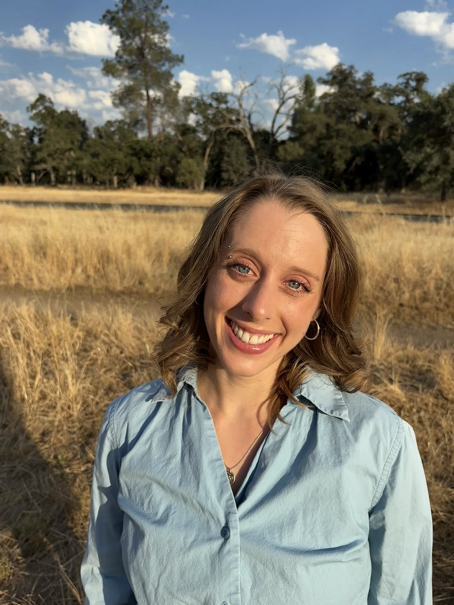 photo of andie samay in a light blue top in bidwell park with grasses and trees in the background