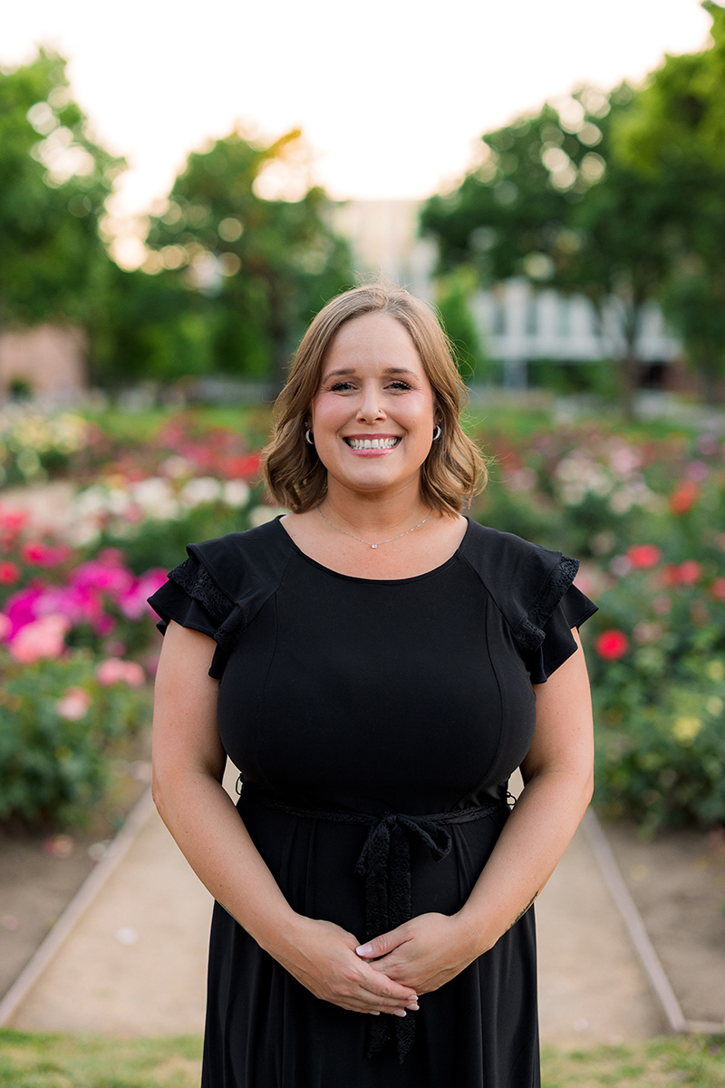 jessica martin in black with flowers in the background